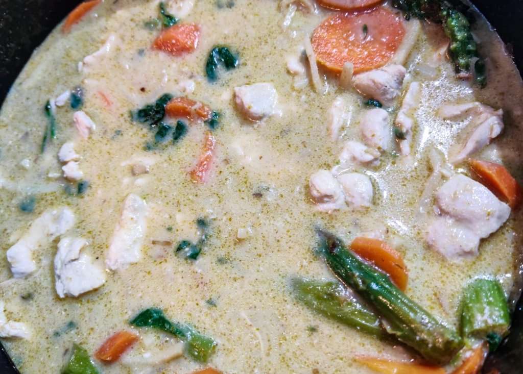 Thai green curry with chicken, greens  and carrots in a pot