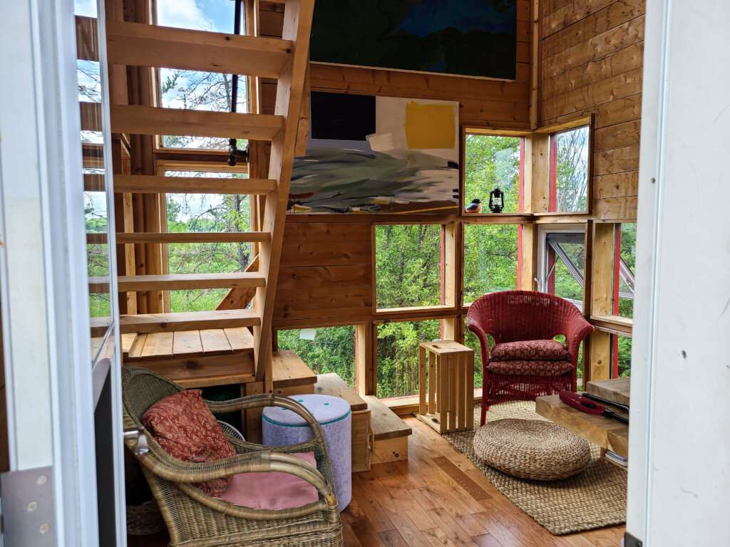 two chairs with cushions inside a wooded cabin with stairs going up