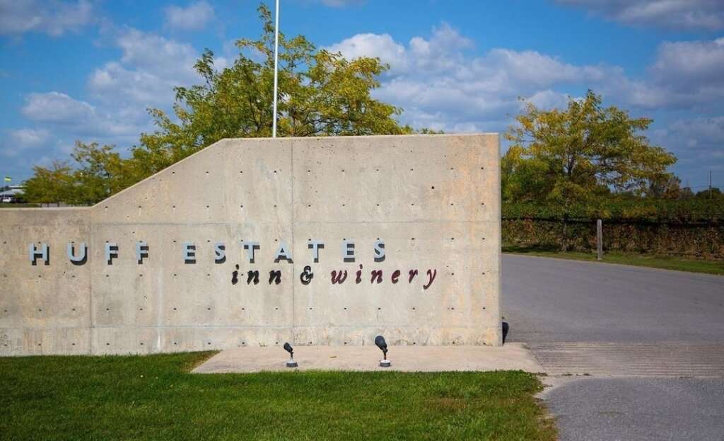huff estates inn and winery entrance sign on a cement wall as one of the best wineries in Prince Edward County 