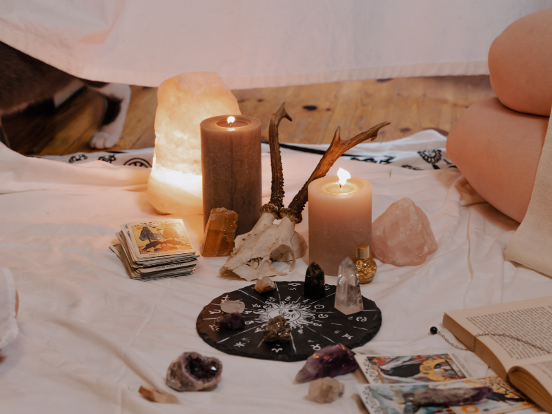 candles that are a flame, with crystals, tarot cards on a white blanket to signify manifestation techniques