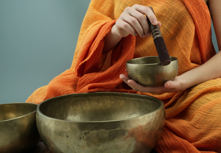 3 different sizes of Tibetan sounding bowls with one being held and used in hand for the purpose of sound therapy healing to signify manifestation techniques