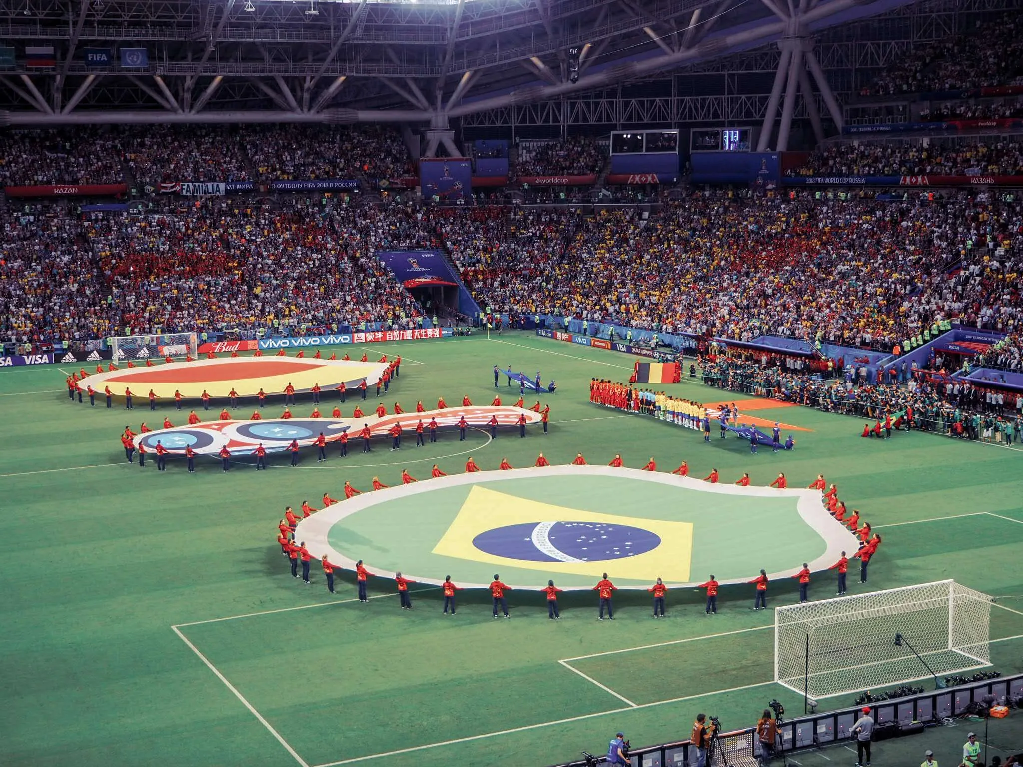 Soccer filed at FIFA world cup 2018. Beligum and Brazil flags are held between the goal posts with a canvas of the cup in the middle.