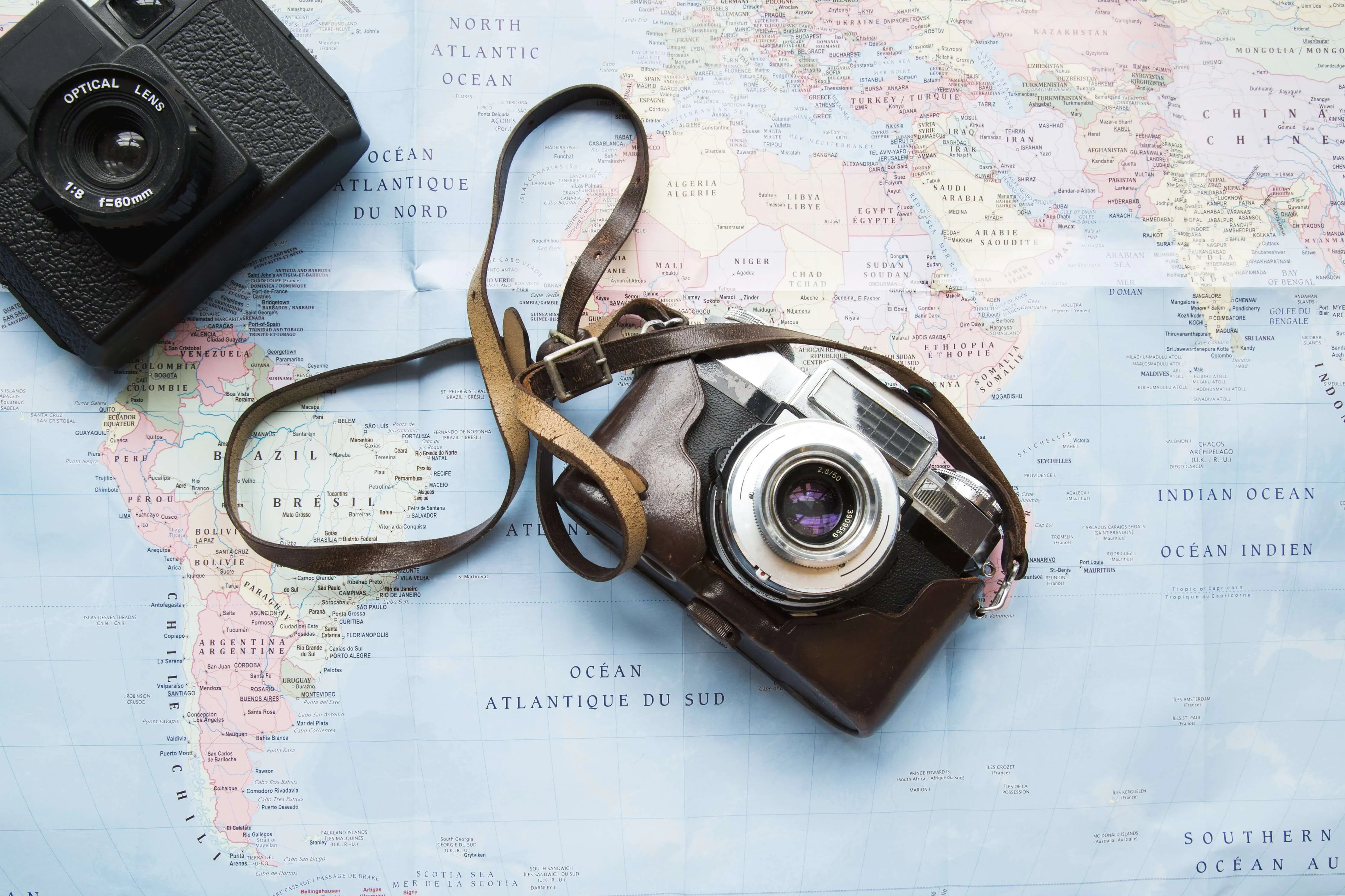 A map of the world with a camera to the right corner and a vintage camera in the middle for a carry-on holiday packing list