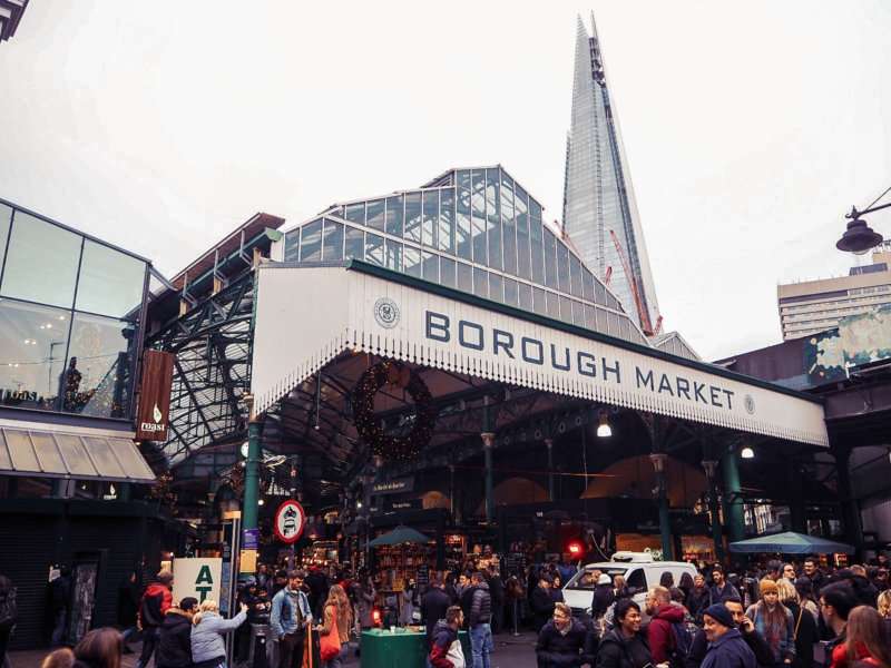 a market space with people surrounding it and a tall pointy building to the right side of it