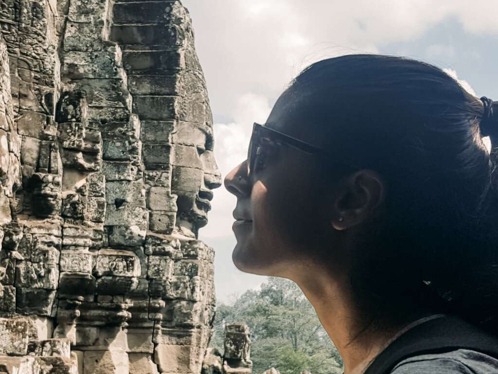the side profile of a solo woman with sunglasses facing a statue nose to nose 