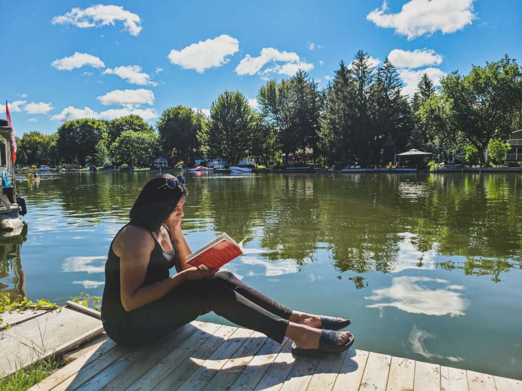 a woman wearing all black, reading life lessons while next to the water