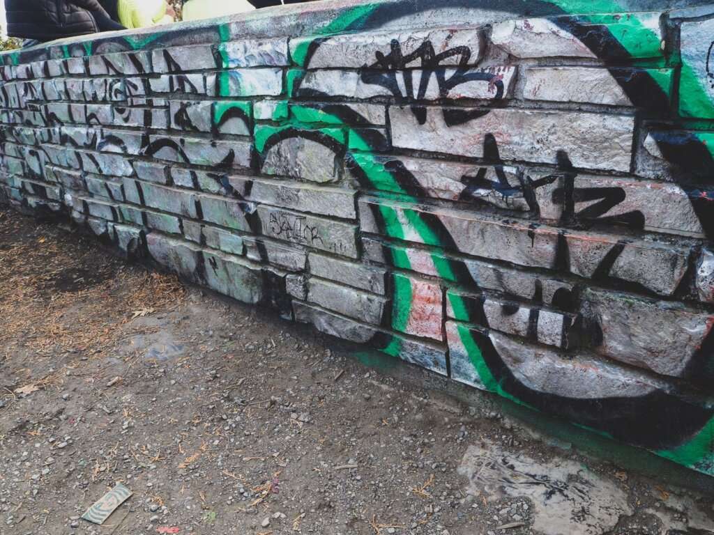 a grey wall with black and green graffiti
