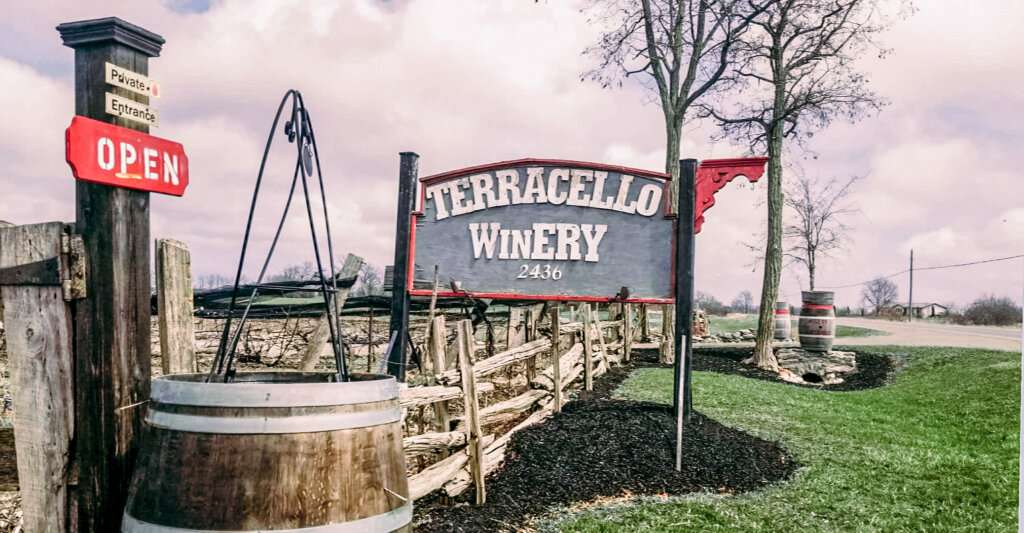 Terracello Winery with green grass, wine barrels and sign as one of the best wineries in Prince Edward County