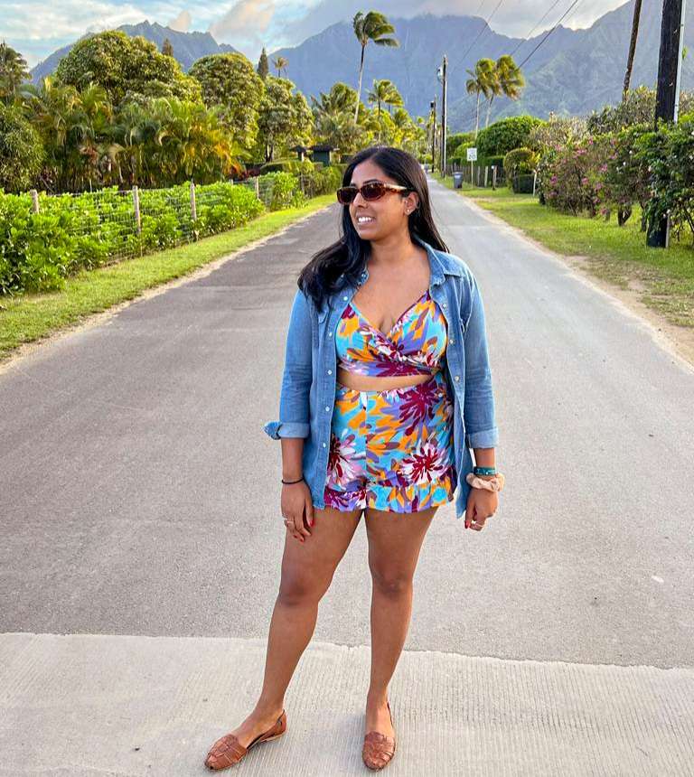 a brown woman standing on the road in front of palm trees and mountains in dopamine dressing to spring clean your life 